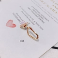 Detalle de pendiente geométrico en oro claro con piedra rosa sobre una invitación - Anillo Colgante de Cono Rosa (13#)
