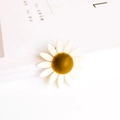Macro shot of white daisy flower jewelry charm with yellow core on a white book - White Daisy Style (2#)