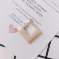 Détail d'une boucle d'oreille carrée géométrique dorée avec finition en émail - Café au Lait