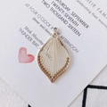 Macro detail of leaf-shaped gold metal charm with white thread weaving for DIY jewelry - Off White