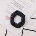 Dettaglio macro di anello rotondo in acrilico nero intrecciato su sfondo di carta nozze - Nero