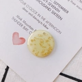 Macro shot of round acrylic pendant with gold foil flakes on decorative white card - Round Gold Foil Pendant (KP2625) / Yellow