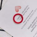 Nahaufnahme eines roten geflochtenen Rings auf minimalistischem Grußkarten-Hintergrund - Rot