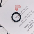 Detail eines schwarzen Silikonrings mit geflochtener Textur auf einer Präsentationskarte - Schwarz