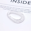 Détail d'une bague en résine marbrée blanche de forme ovale irrégulière sur fond minimaliste - Motif Marbre Mica (9#)