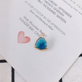 Close-up of a gold-plated triangle pendant with a deep blue faceted crystal and intricate bezel - Royal Blue