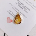 Detailed view of teardrop resin pendant with gold metal frame on textured fabric - 3# Amber Yellow
