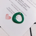 Detailed view of a green enamel round charm with gold metal edges for DIY jewelry making - Green