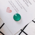 Macro shot of polished green emerald glass bead for jewelry making on a decorative card - Green