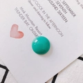 Close-up of semi-circular turquoise resin jewelry accessories on a white textured fabric - Blue
