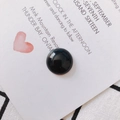 Close-up of a polished round black resin cabochon for DIY jewelry and earring making - Black