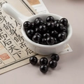 Polished 10mm black pearwood loose beads in a white bowl for DIY jewelry making - 1 Piece Pack / Ebony