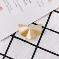 Macro shot of matte gold fan shaped DIY earring pendant on black and white plaid fabric - Matte Gold