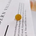 Detail showing a yellow enamel round pendant charm with golden serrated metal edges - Yellow