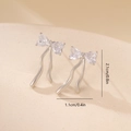 Macro detail of bow-shaped stud earrings with zircon hearts and metal ribbons - Platinum Bowknot Tassel Style (MYYX00654)