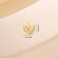 Vista macro di un ciondolo a cuore dorato da 1cm con lettera V in zircone su pietra - Lettera V-Oro