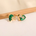 Dettaglio di orecchini a cuore in oro con zircone verde smeraldo e accento di fiocco - Verde