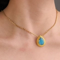 Elegante collana a goccia d'oro con zircone blu indossata sul collo di una donna - A forma di goccia / Blu