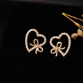 Eleganti orecchini a cuore dorati con zirconi e fiocco dorato su velluto nero - Cuore con Decorazione a Fiocco Oro (ED12543)
