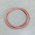 Makro-Detail von dreilagigem roségoldenem Spiral-Gitarrensaiten-Armband auf Holz - Dunkelroségold