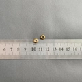 Detailed size view of 4mm gold beaded charms with white inlay on a measuring scale - Spacing Bead (7x3.5x1.8mm) / 2 Pcs/Set / Gold