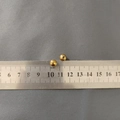 Detail view of 4mm golden stainless steel beads measured with a ruler on a textured surface - Ball Screw Nut (7mm) / 1 Piece / Gold