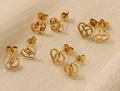 Close-up of golden heart-shaped stud earrings featuring intricate zodiac sign cutouts - Taurus / Gold