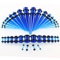 Makroansicht blauer Acryl-Dehnstäbe und Plugs mit schwarzen Gummiringen für das Ohr - Transparentes Blau