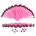 Detailliertes Set aus rosa Acryl-Ohrdehnbändern und Plugs mit schwarzen Gummiringen auf Weiß - Rosa Schmuckset
