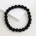 Macro shot of 21 polished 8mm black natural stone beads on a minimalist elastic bracelet - Polished Black Stone Bracelet