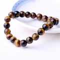 Macro view of polished tiger eye stone beads on a ceramic plate with silk luster texture - Tiger's Eye