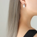Polished silver heart-shaped hoop earrings in stainless steel on a female model - Steel