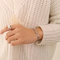 Ensemble bracelet fleur ajouré argent et bague géométrique sur pull en maille - Acier