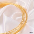 Macro shot of 0.4mm 18K gold-plated jewelry wire on elegant white silk background - 0.4