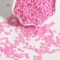 Roze ondoorzichtige glazen kralen voor DIY sieraden in een witte keramieken kom - Roze