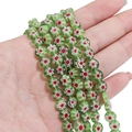 Flat round green millefiori glass beads with white and red flower patterns for DIY jewelry - Green