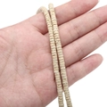 Strand of beige volcanic stone heishi beads held by hand for DIY jewelry making - Heishi Disc Style / 2x4mm, Aperture approx. 1mm, 40cm/Strand, approx. 185 beads / Beige