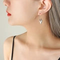 Orecchini a cuore minimalisti in acciaio al titanio argento indossati da modella - Colore acciaio