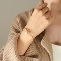 Elegant rose gold titanium steel bracelet with white pearl charm on a model's wrist - Rose Gold
