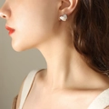 Elegantes pendientes de corazón plateados con acabado pulido mostrados en una modelo - Color acero