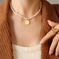 Elegant pearl necklace with golden letter G shell pendant on a model with ring - Letter G