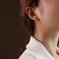 Minimalist long teardrop earrings in polished gold finish worn by a fashion model - Steel