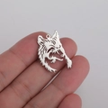Detailed close-up of a vintage silver-colored wolf head hollow pendant in hand - Steel