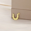 Macro detail of gold horseshoe pendant for DIY jewelry making on silk fabric - Gold