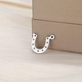 Detailed macro shot of a silver horseshoe charm with decorative holes for DIY jewelry making - Steel