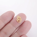 Macro detail van een kleine gouden anatomische hart hanger voor DIY sieraden op een vingertop - Goud