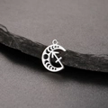 Detailed macro shot of silver crescent moon Sagittarius zodiac pendant on a dark stone - Silver-Sagittarius