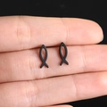 Macro shot of minimalist black titanium small fish stud earrings on a finger - Black