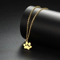 Close-up of a polished golden cat paw pendant on a fine metal chain over a black background - Gold
