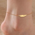 Detalle de un colgante de pluma en oro de 18K en una tobillera usada en la playa - Dorado - Una Capa